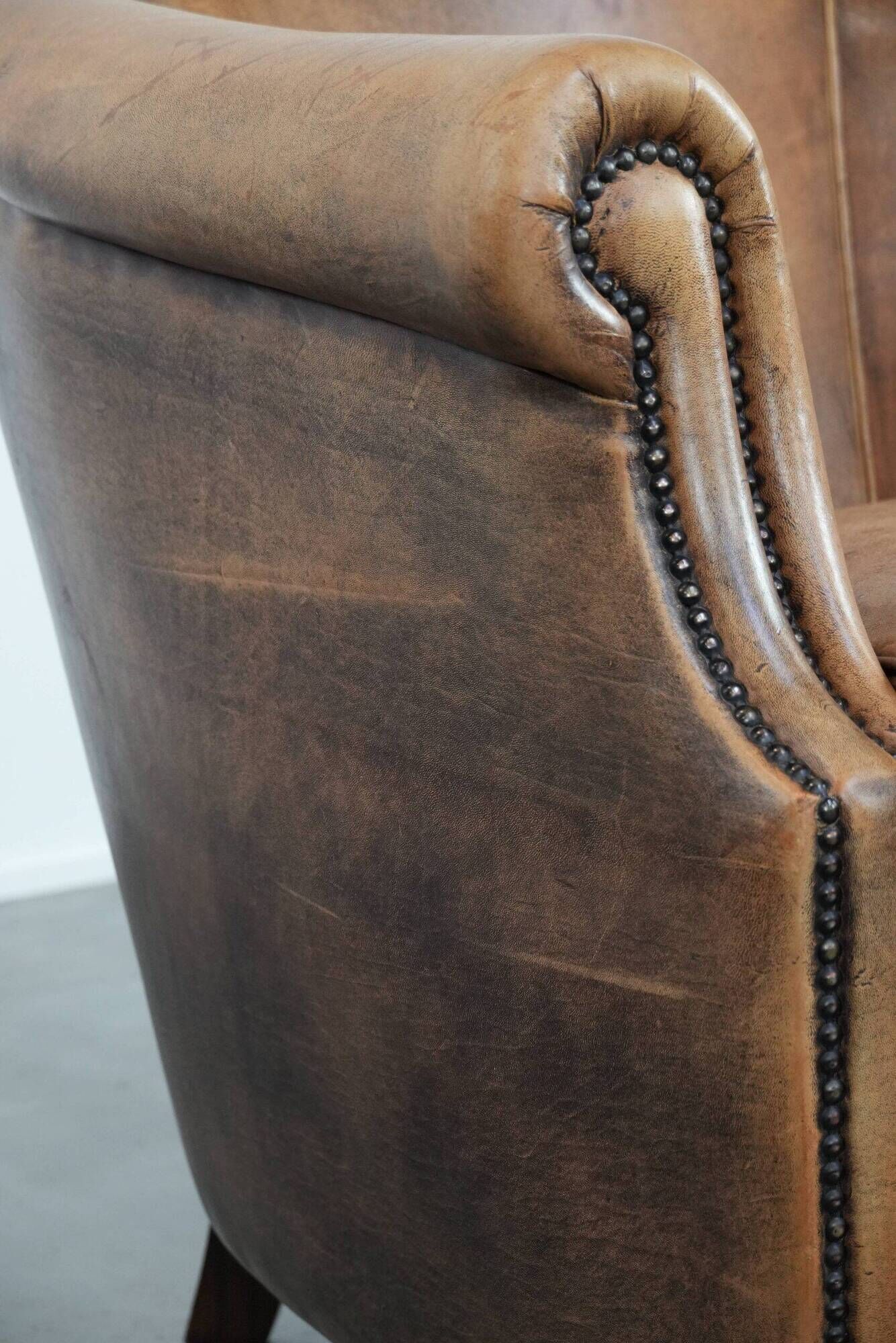 Club chair made of sheepskin leather finished with decorative nails