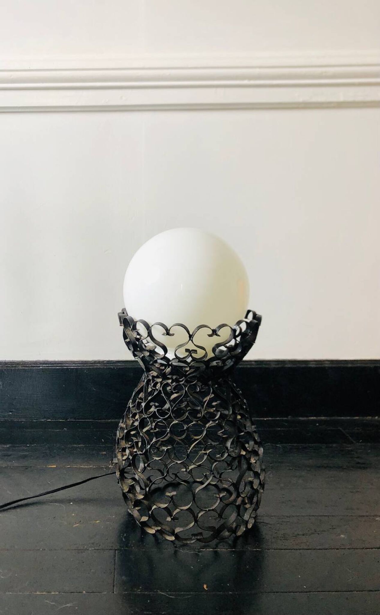 Black wrought iron lamp with a white glass globe.