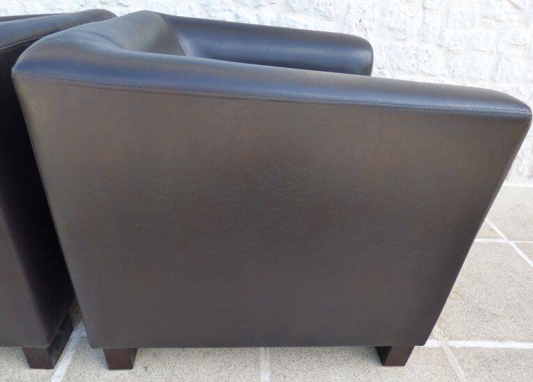 2 club armchairs with a chocolate faux leather seat and backrest and wooden legs.