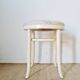 Antique stool with a wooden frame and a cream and green striped fabric seat.