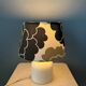 Small Space Age table lamp with a porcelain base and black and white flower shade.