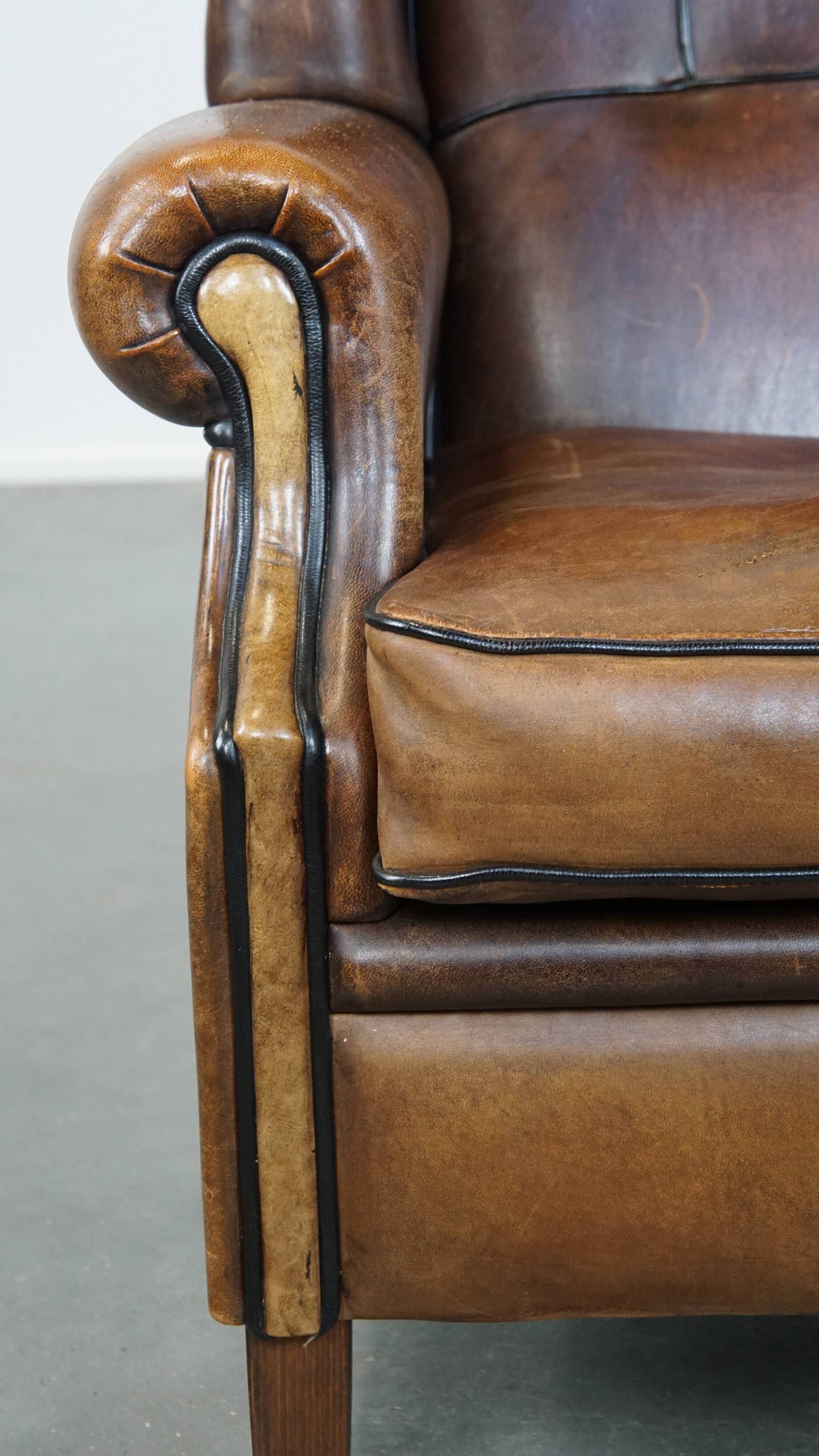 Vintage sheepskin wingback chair finished with black piping
