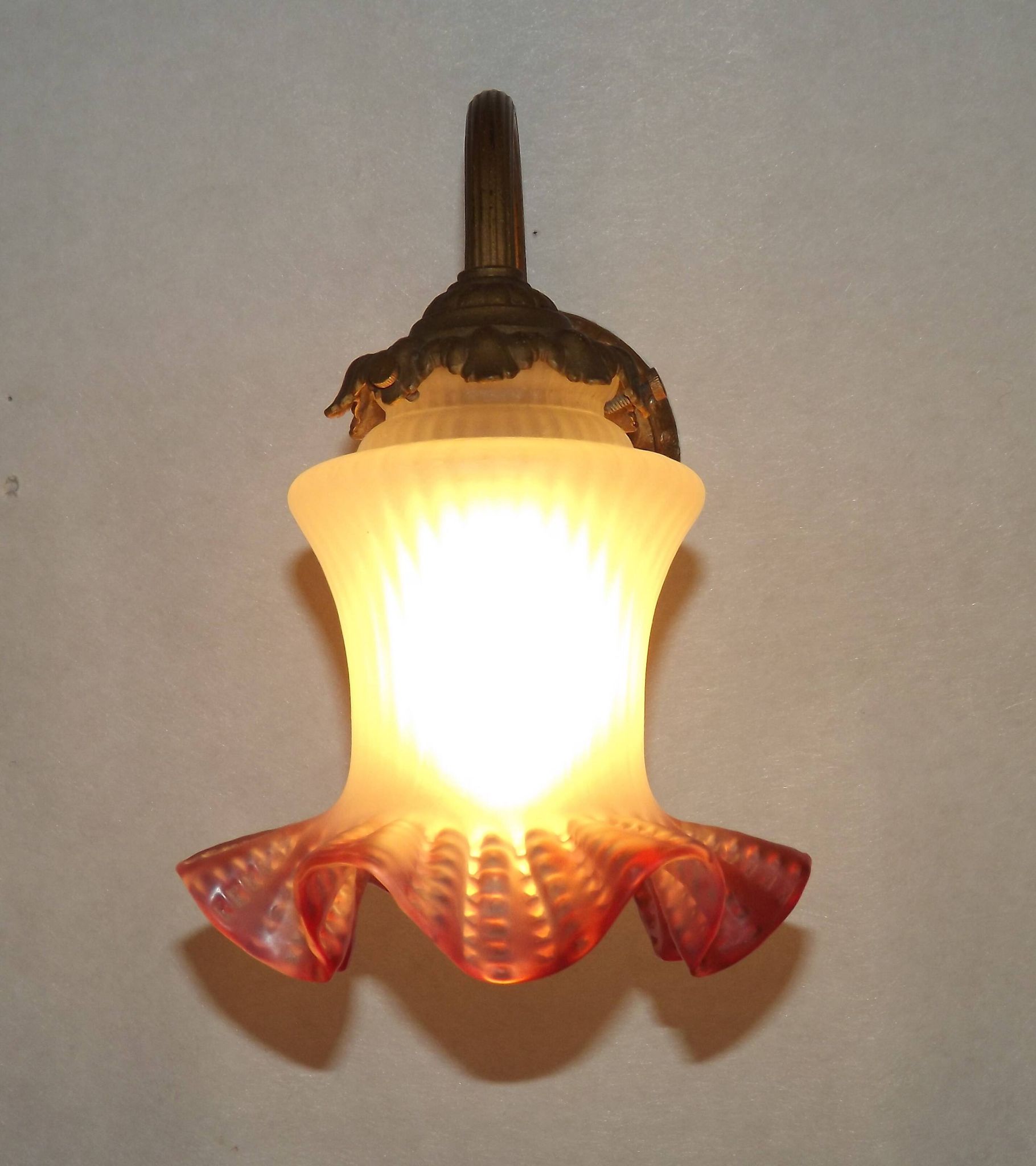 French Art Nouveau wall sconce in bronze with a white and pink glass shade.