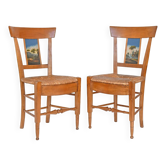 Pair of chairs with slatted backs and painted bands depicting animated landscapes.