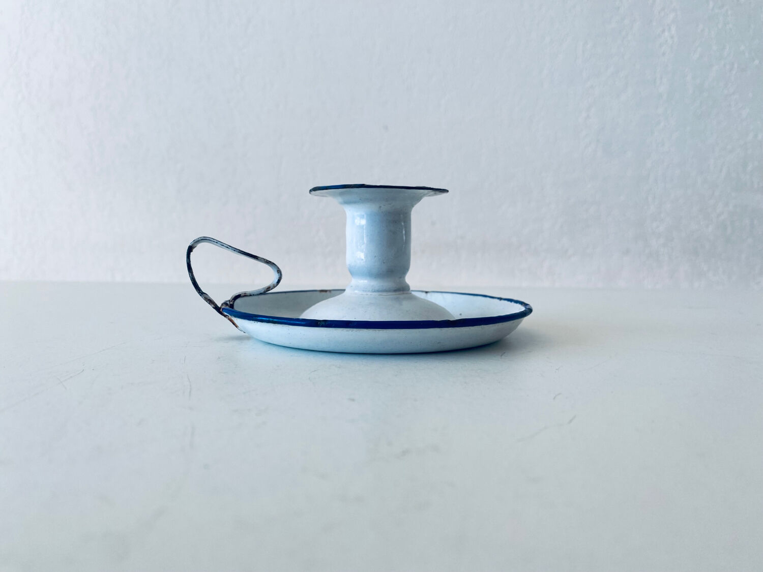 Old candle holder in white enameled metal