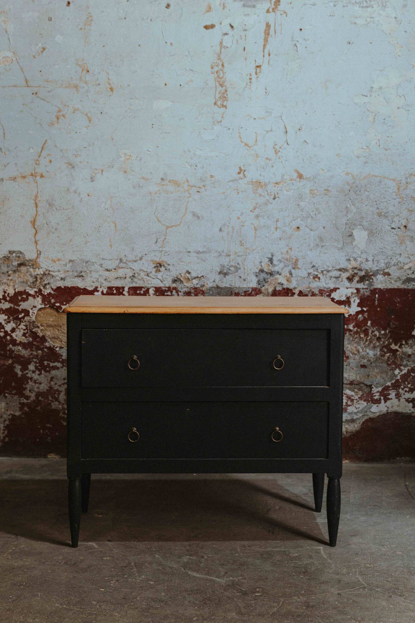 Commode noire à 2 tiroirs, plateau en bois brut et pied fuselés