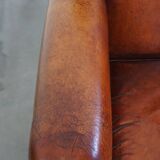 Sheepskin leather armchair in a cognac color with black piping