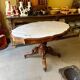 Table with a carved wooden frame and grey marble top on wheels, measuring 130 x 82 cm.