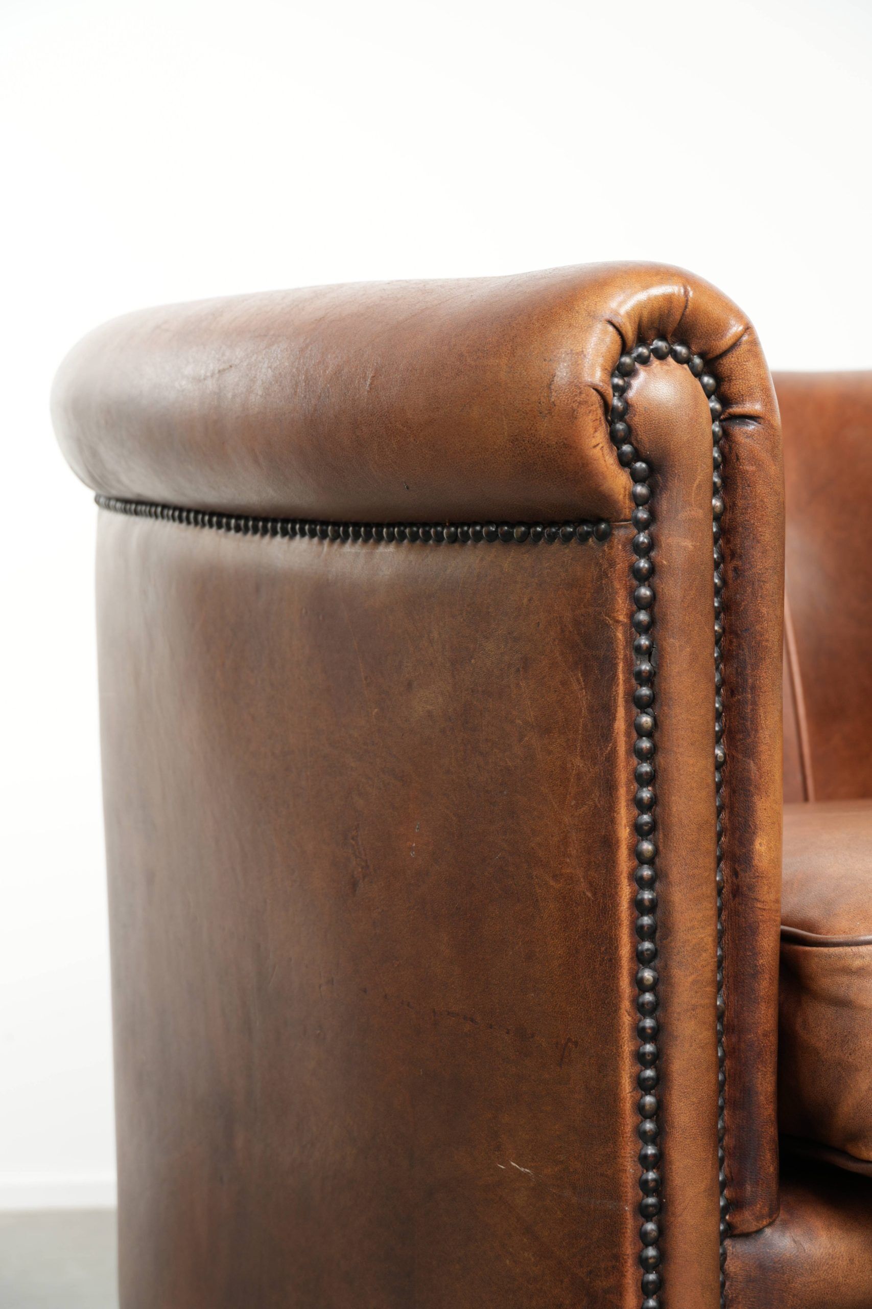 Sheepskin club armchair with a cognac colour finished with decorative nails