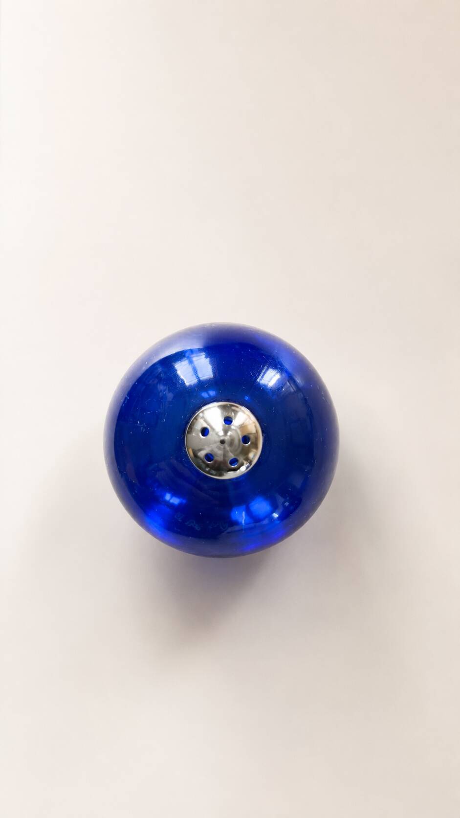 Bright blue glass salt and pepper shakers in a spherical shape.