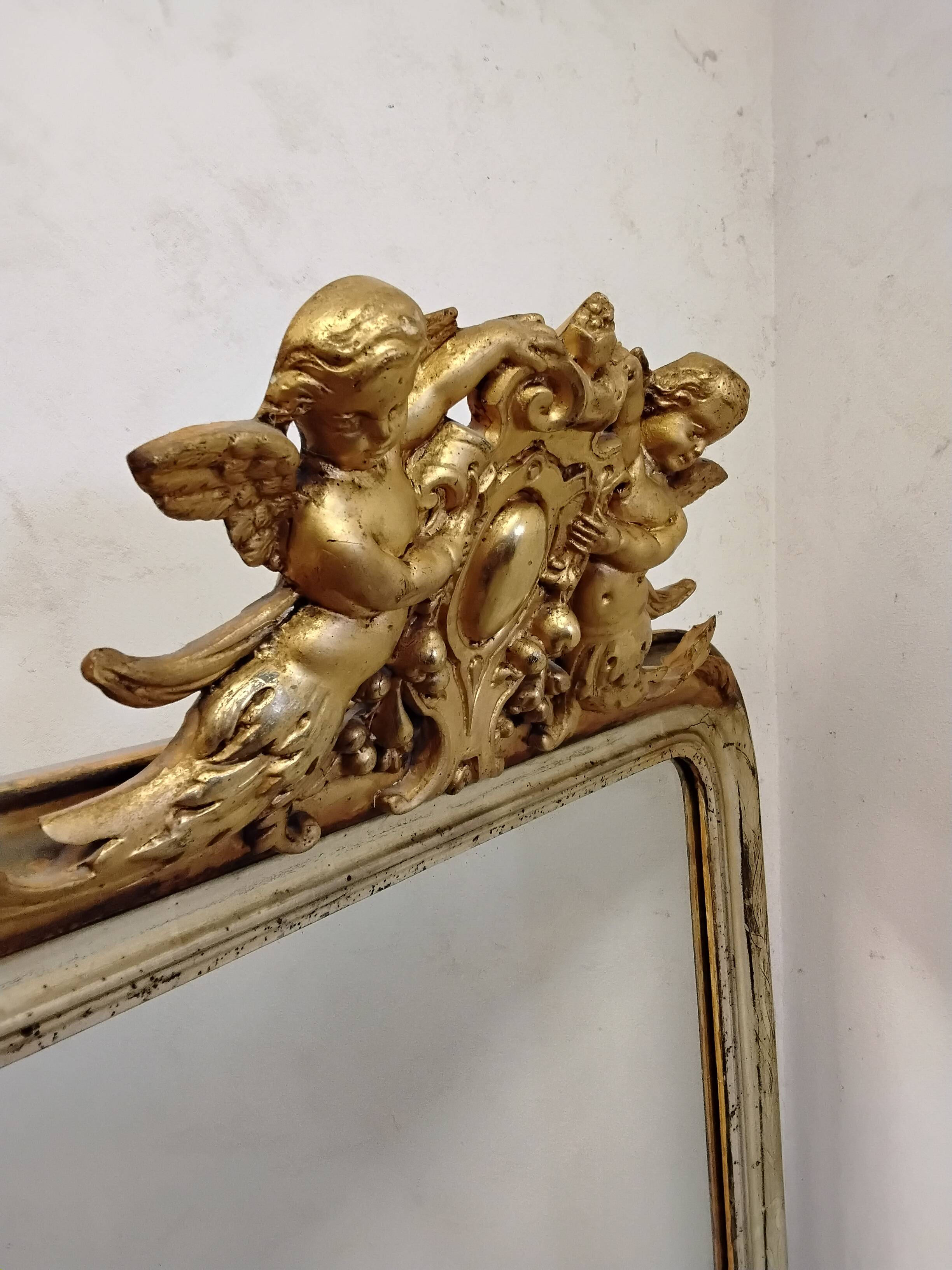 Antique mirror with a gilded frame and cherubs.