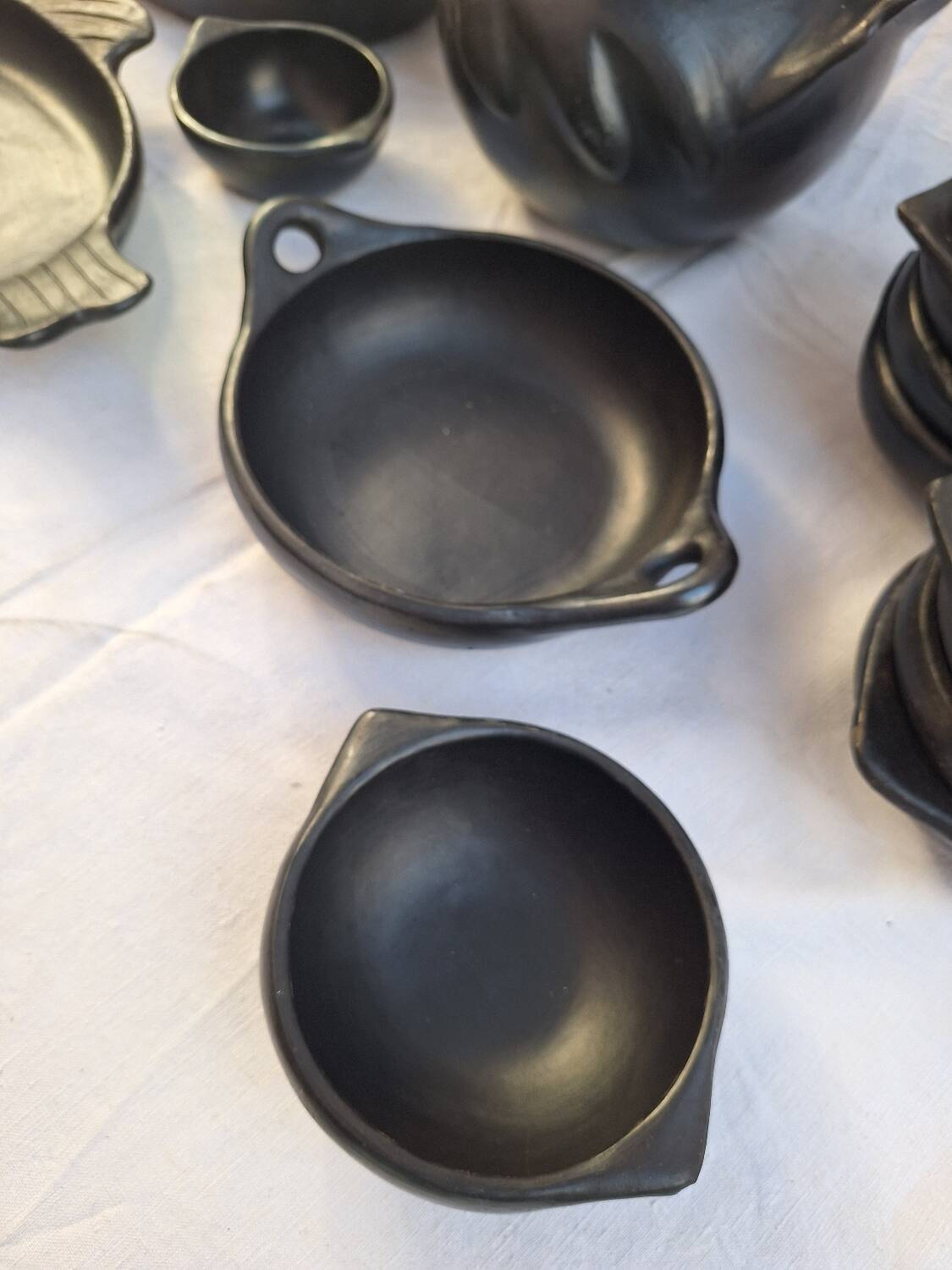 Black terracotta dinnerware set from La Chamba in Colombia. Set of 13 pieces.