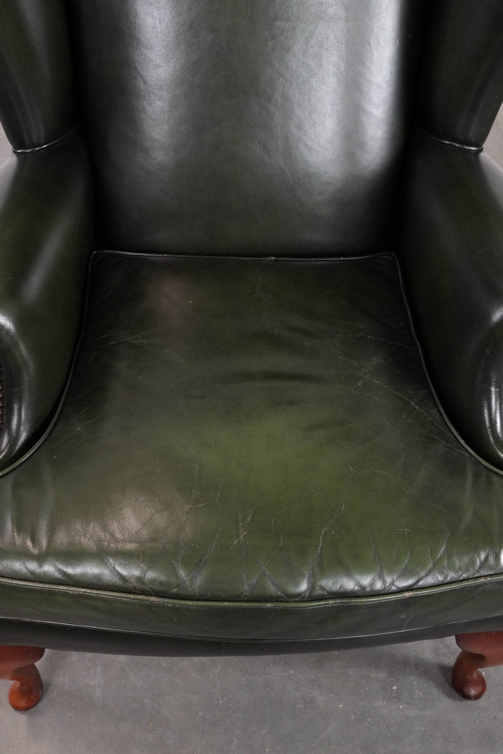 Smooth classic cowhide Chesterfield armchair in a stylish dark green color