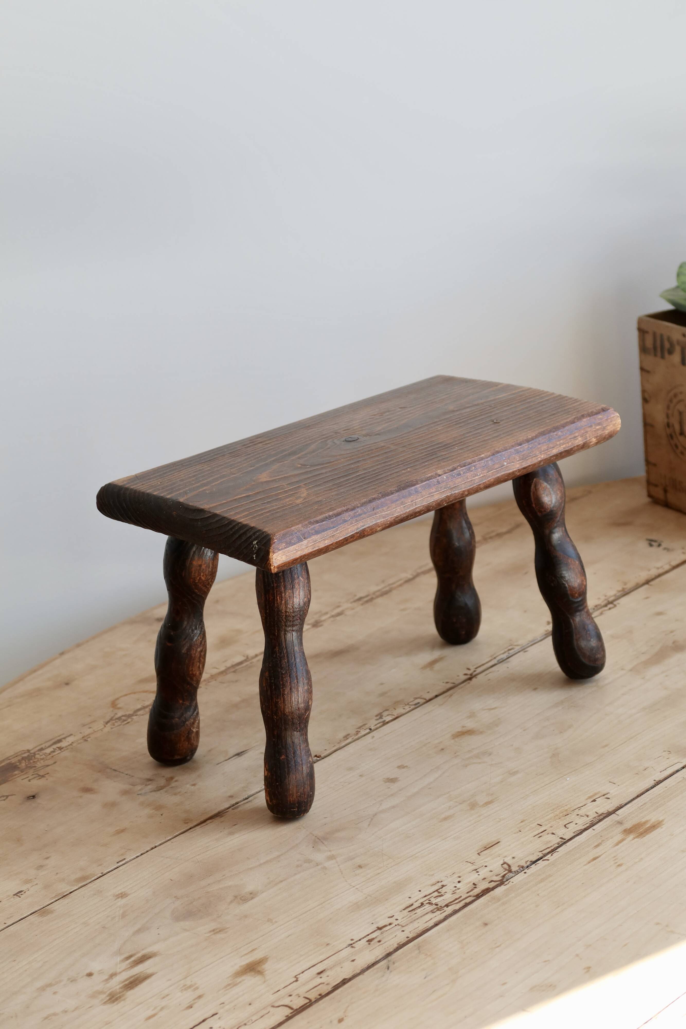 Vintage rectangular stool in dark wood with turned legs.