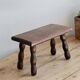Vintage rectangular stool in dark wood with turned legs.