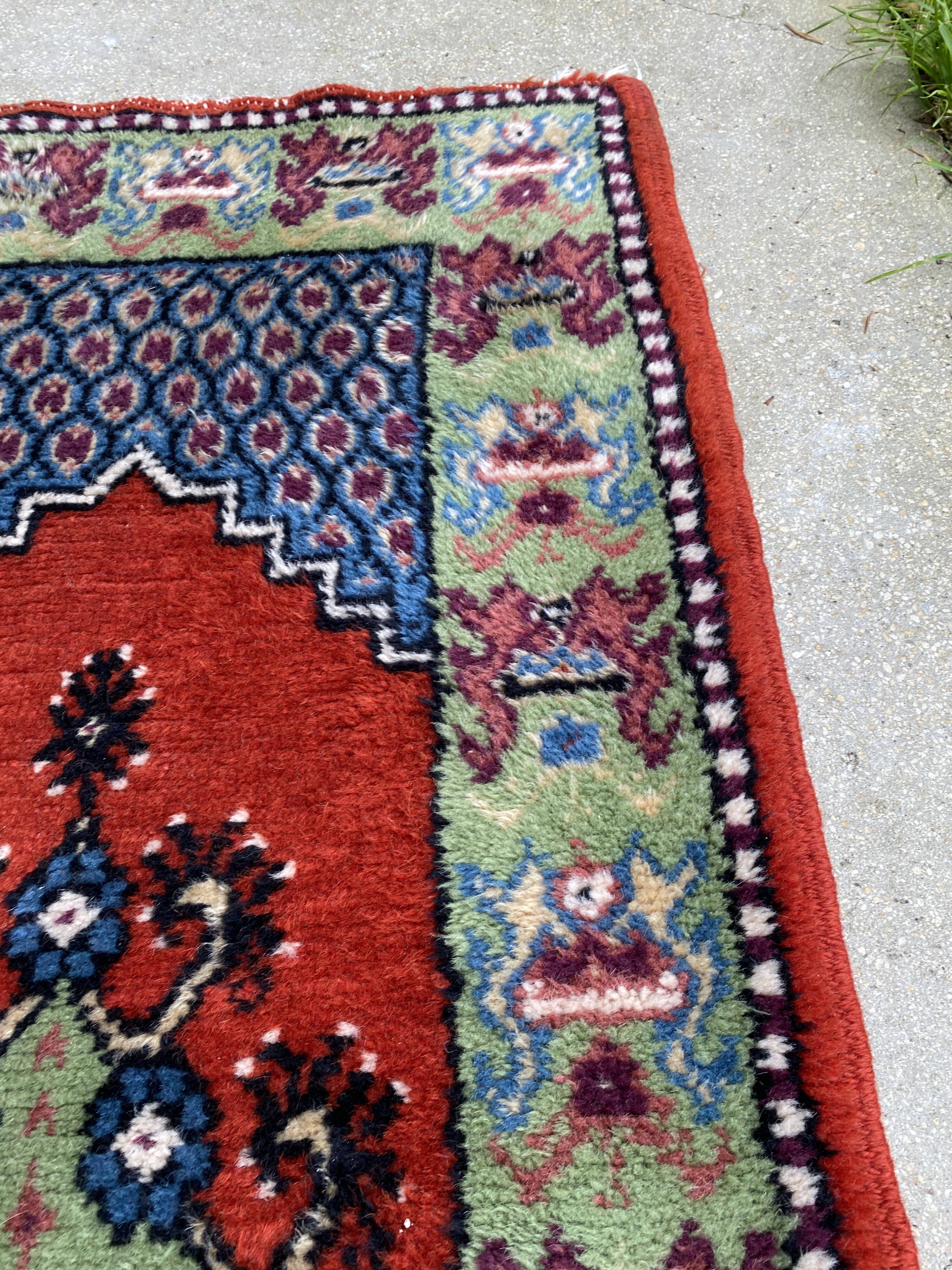 Vintage hand-knotted wool rug with polychrome decoration on a red, blue, green background 150 x 63 cm