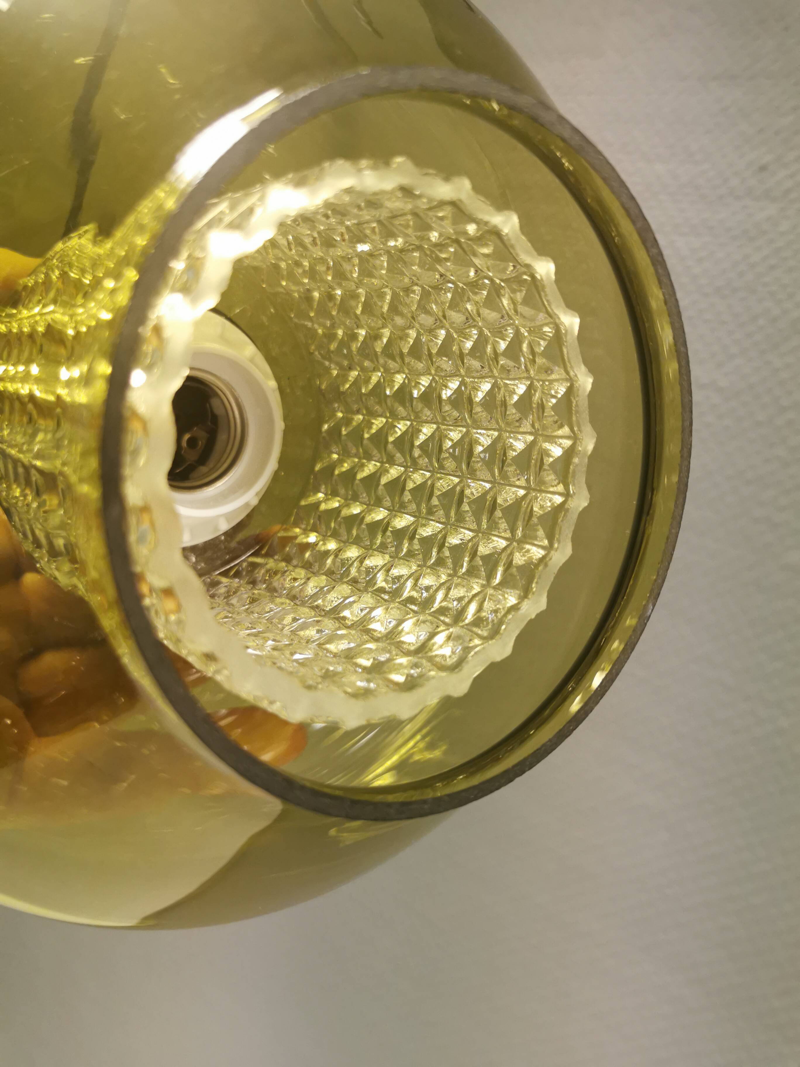 Hanging lamp with an outer shade of olive green glass and an inner shade of clear, crystal glass.