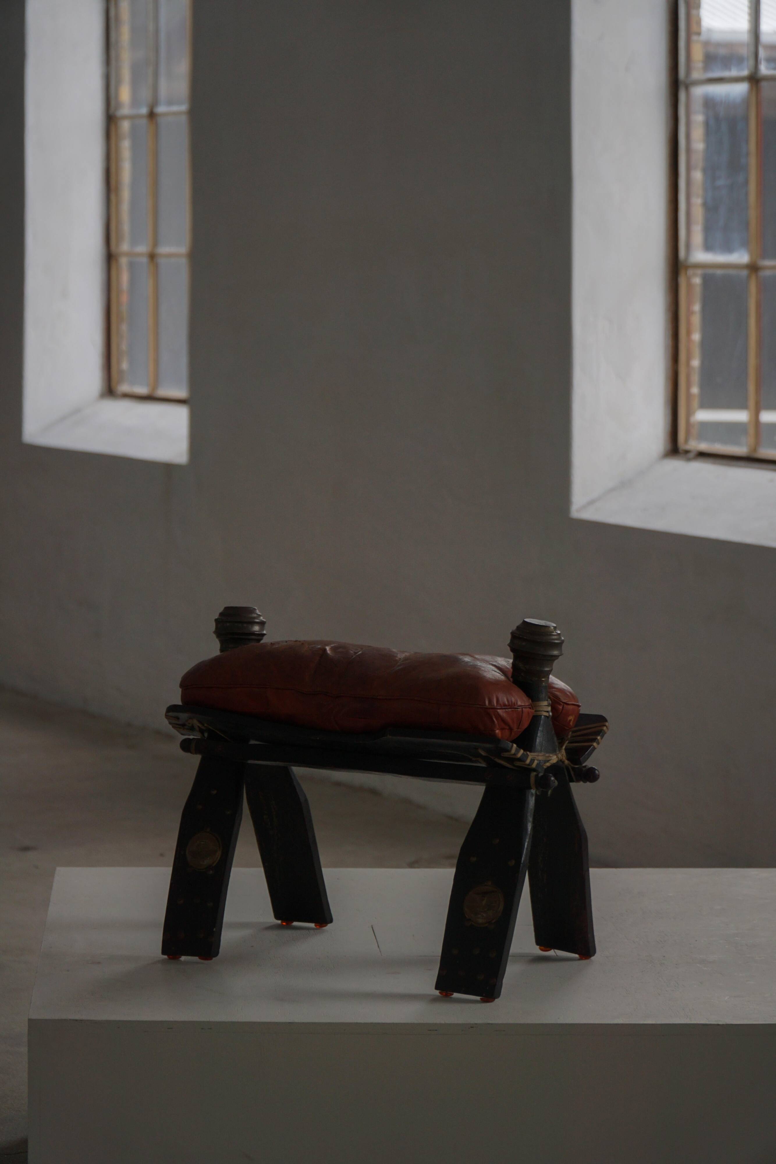 Dark red upholstered camel saddle stool, 20th century, North Africa.