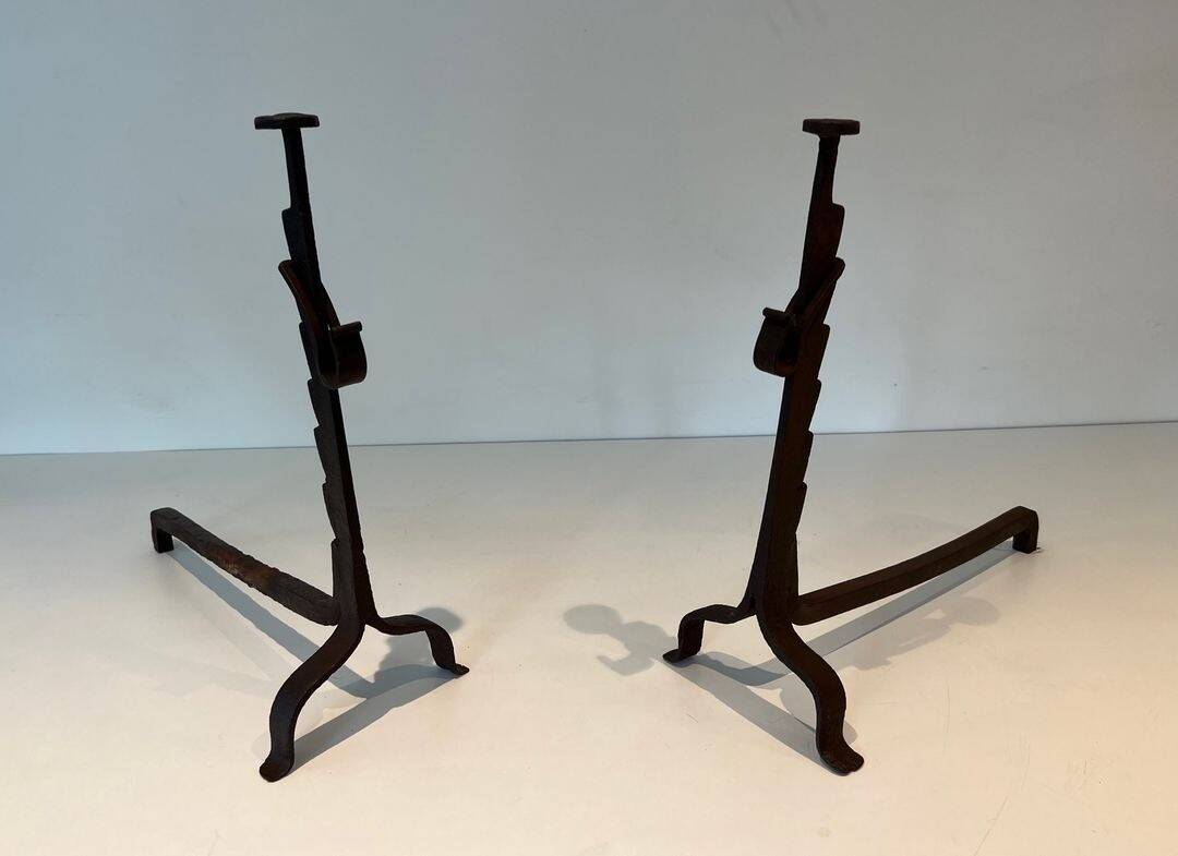 Pair of wrought iron andirons with adjustable supports and tripod feet.