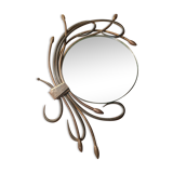 Round mirror surrounded by art deco style metal plants