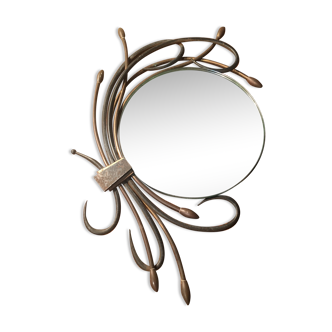 Round mirror surrounded by art deco style metal plants