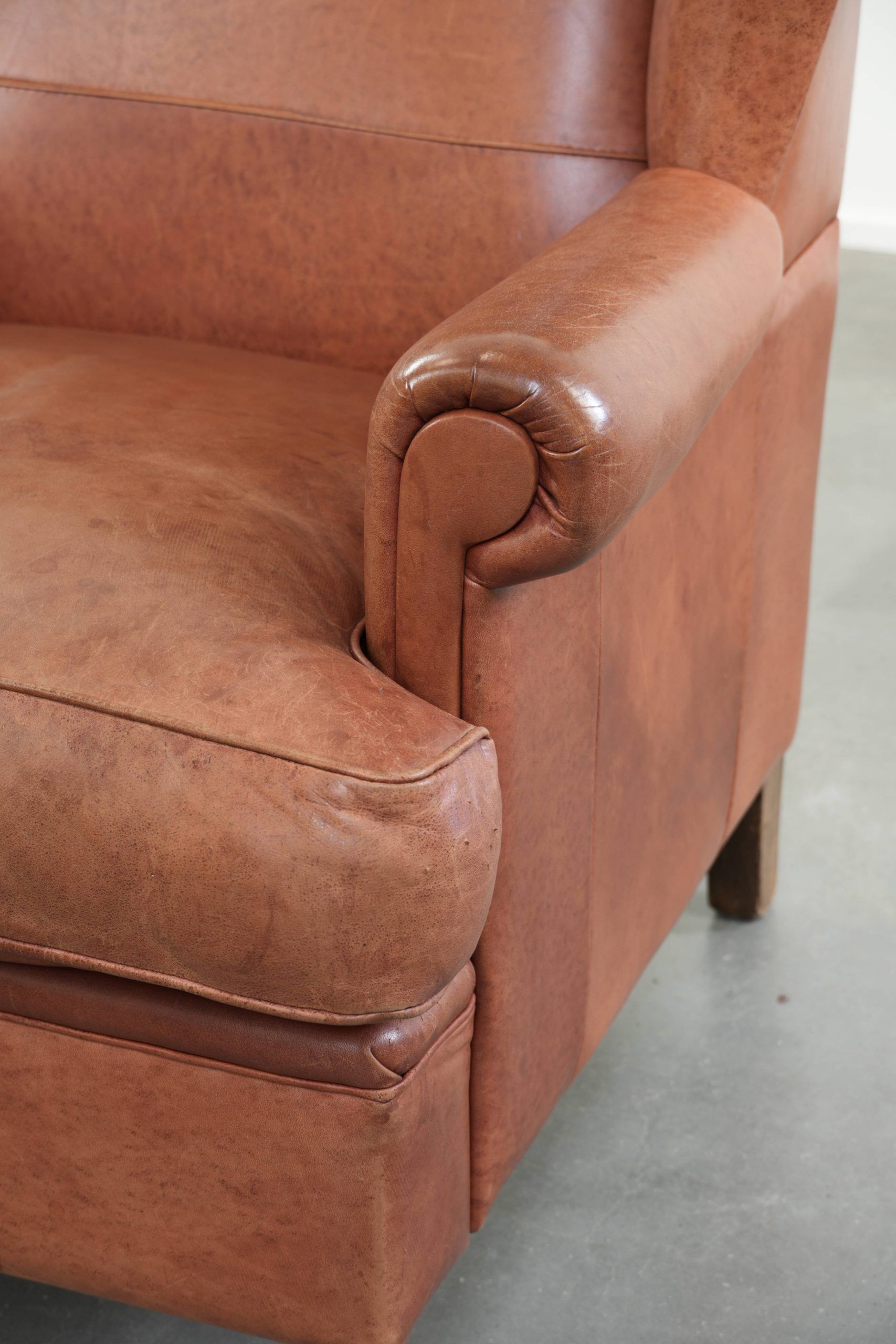 Fauteuil anglais à oreilles de couleur cognac clair en cuir de vache.