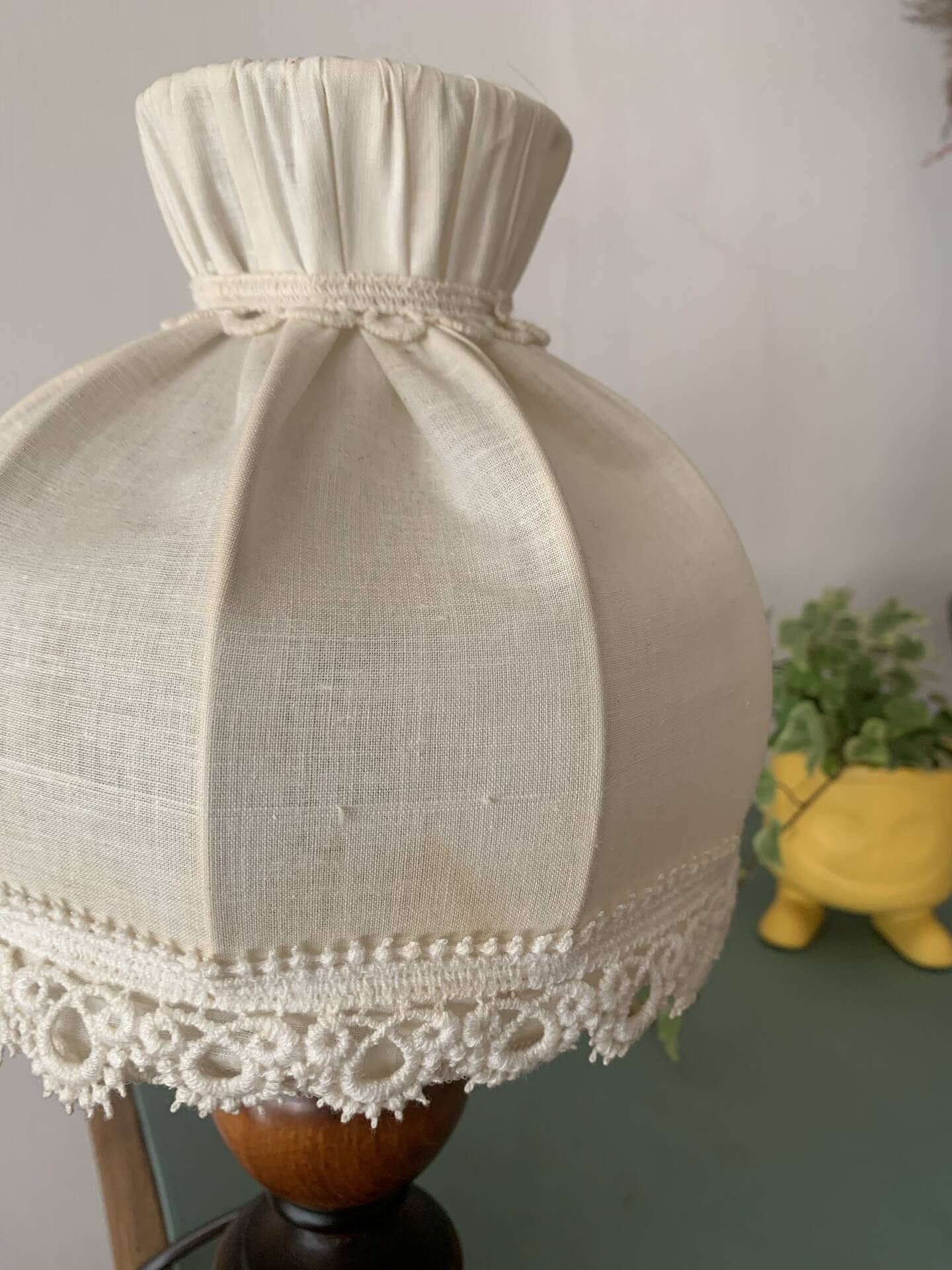 Small vintage wooden turned table lamp with a pleated shade.