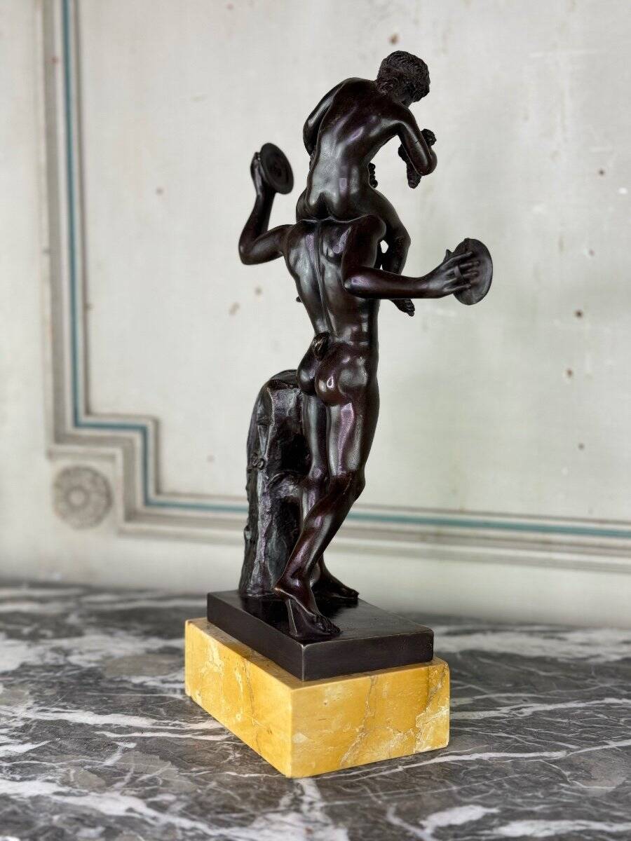 Dionysus on the shoulders of a satyr, bronze after the antique on a yellow Siena base.