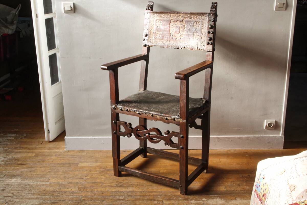 Antique armchair in walnut and studded leather, 17th century