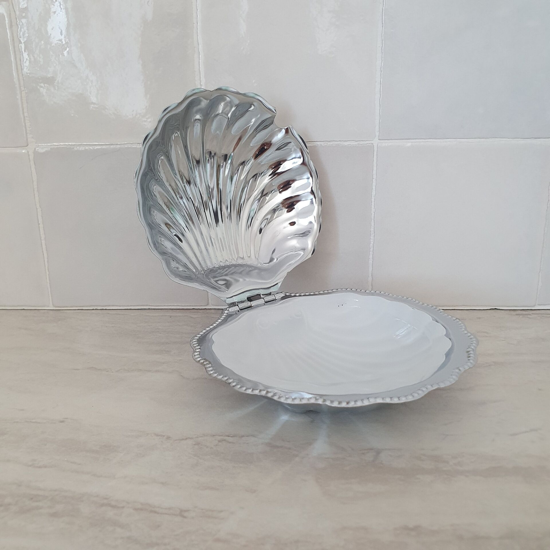 Scallop shell butter dish in stainless steel with its white glass saucer.
