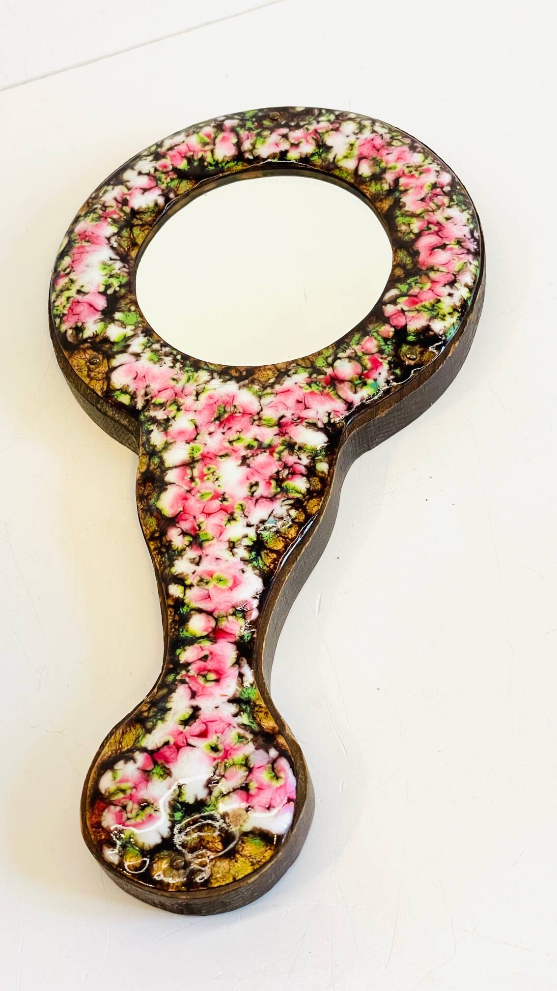 Vintage enameled metal hand mirror on wood