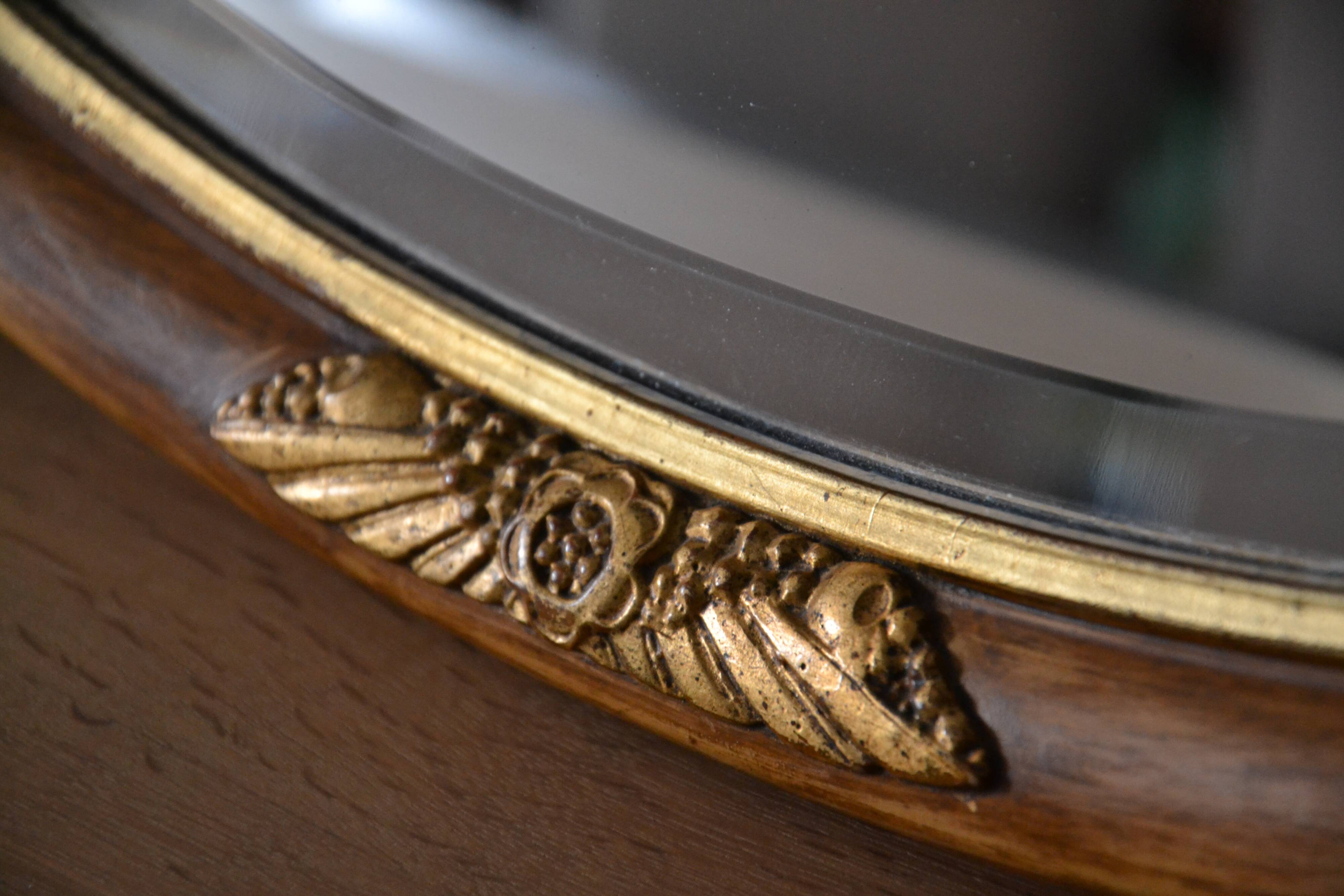 Old oval beveled wooden mirror, partly gilded and carved