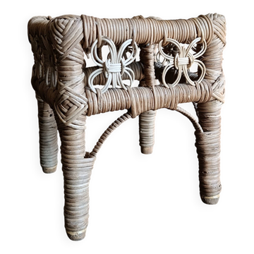Tabouret en osier vintage, petit repose-pieds en rotin tissé et support de plante rustique.