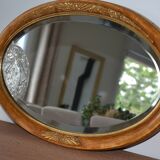 Old oval beveled wooden mirror, partly gilded and carved
