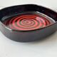 Large decorative ceramic catchall with red and black spiral pattern.