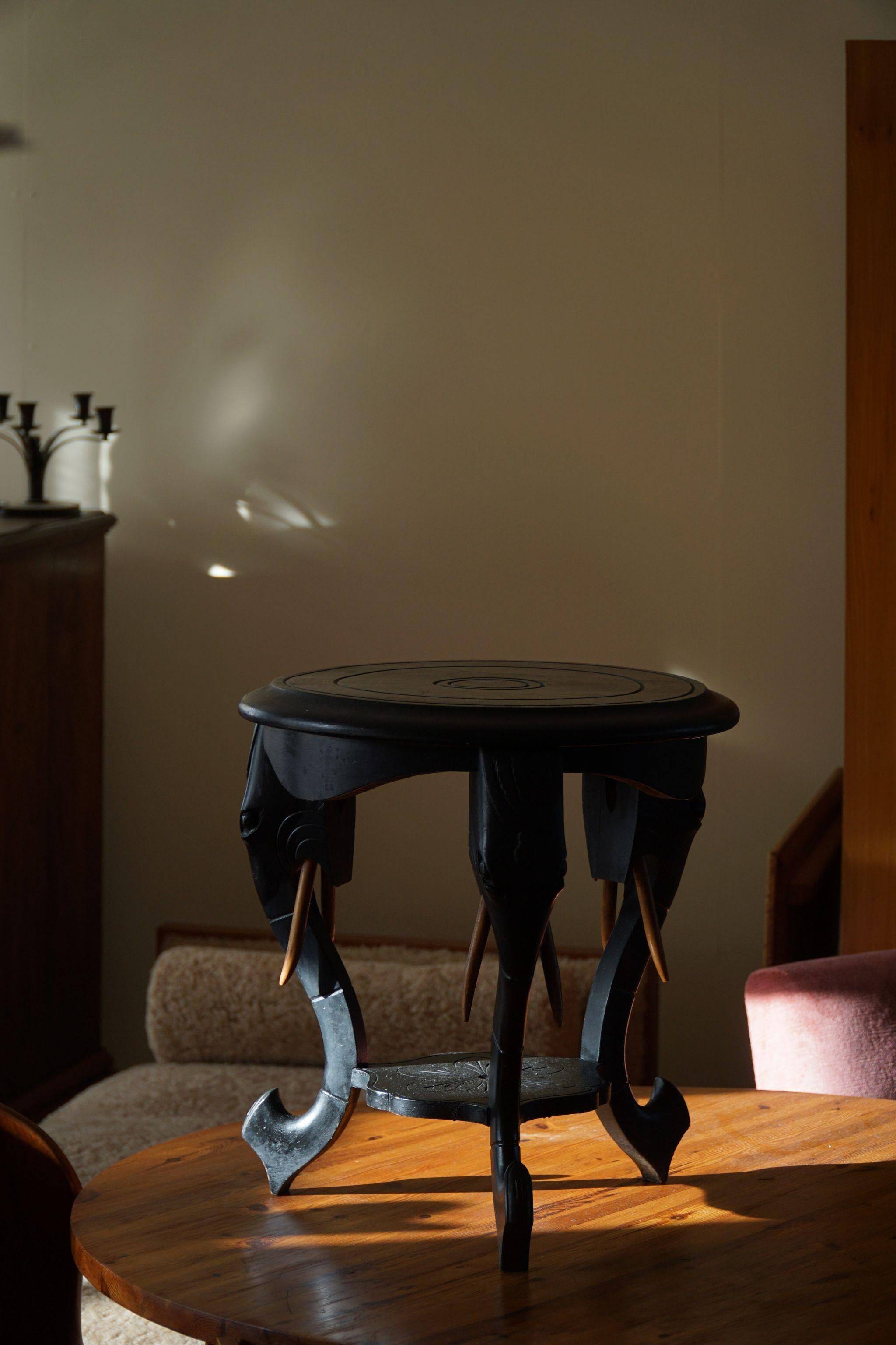 Side table in hardwood ebony with three elephant head-shaped legs, Eastern India, 1920s.