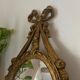 Oval convex witch mirror with golden ribbon mouldings.