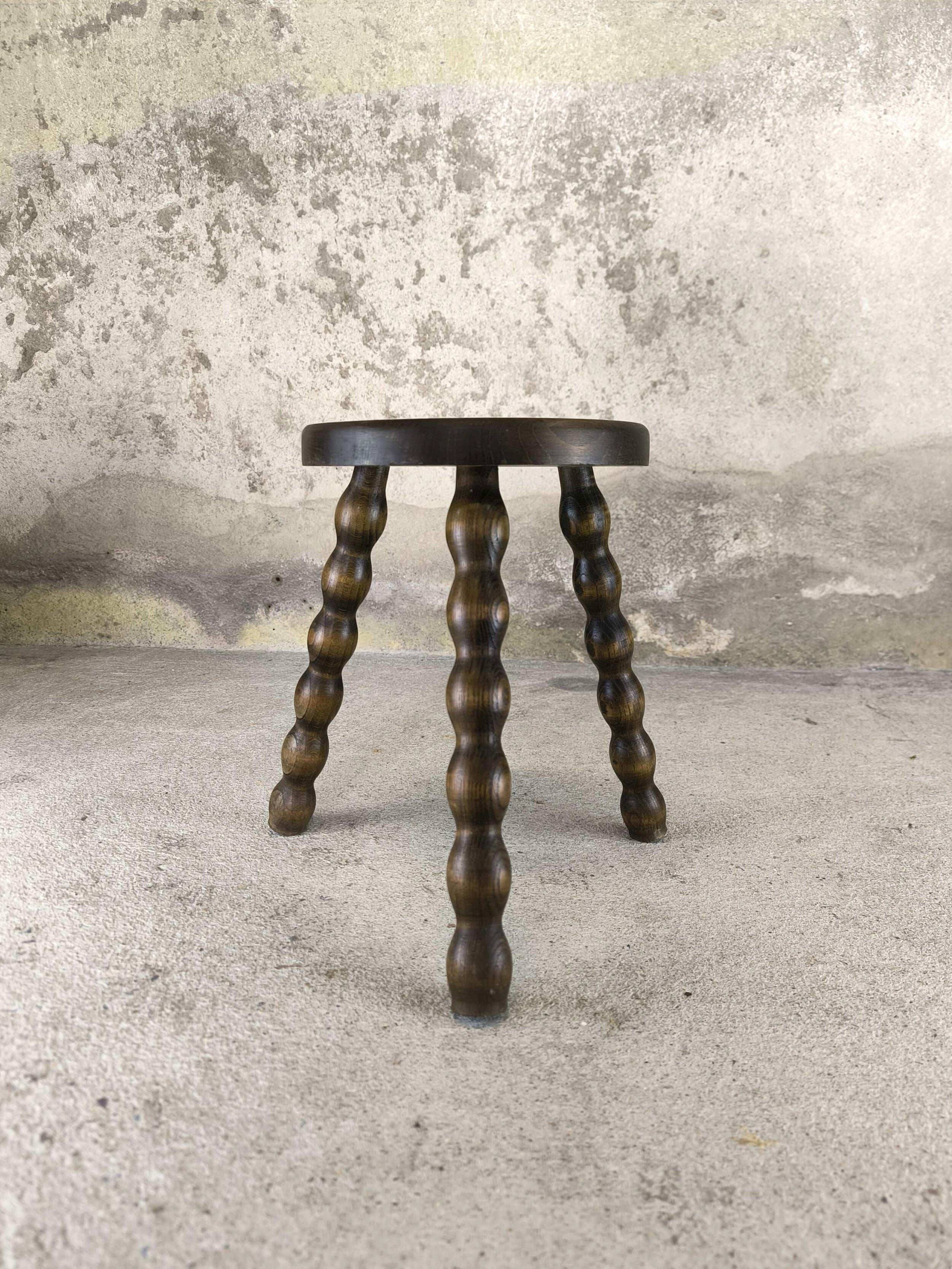 Small three-legged wooden stool with beaded feet.