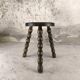 Small three-legged wooden stool with beaded feet.
