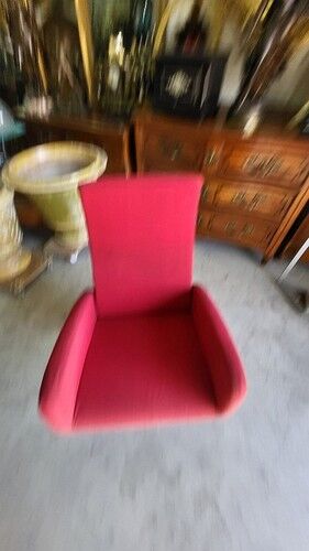 Old cinema chair with a red reclining seat.