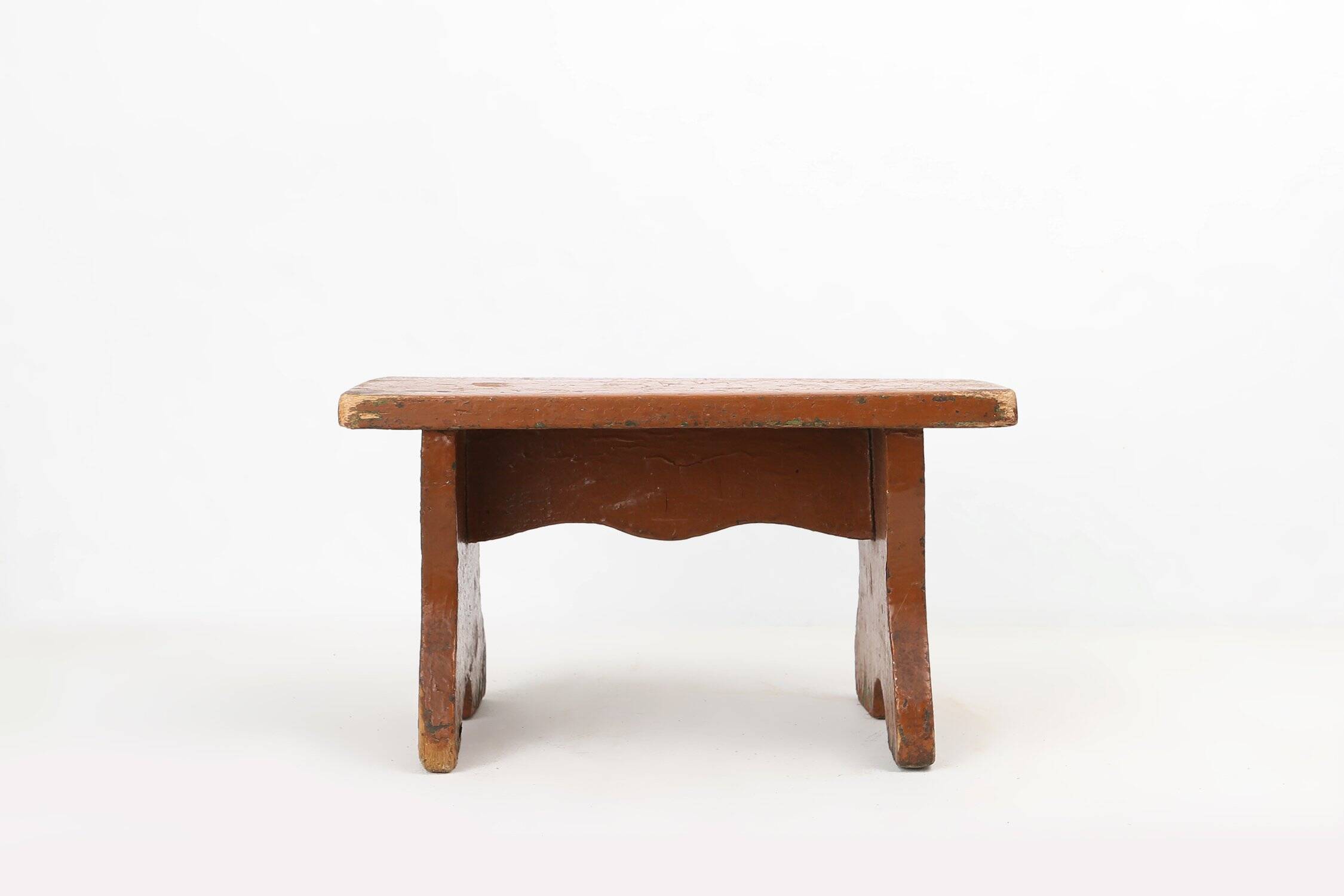 Tabouret bas rustique français en bois peint en terre cuite, années 1890.