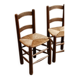Pair of wooden chairs with woven straw seats.