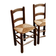 Pair of wooden chairs with woven straw seats.