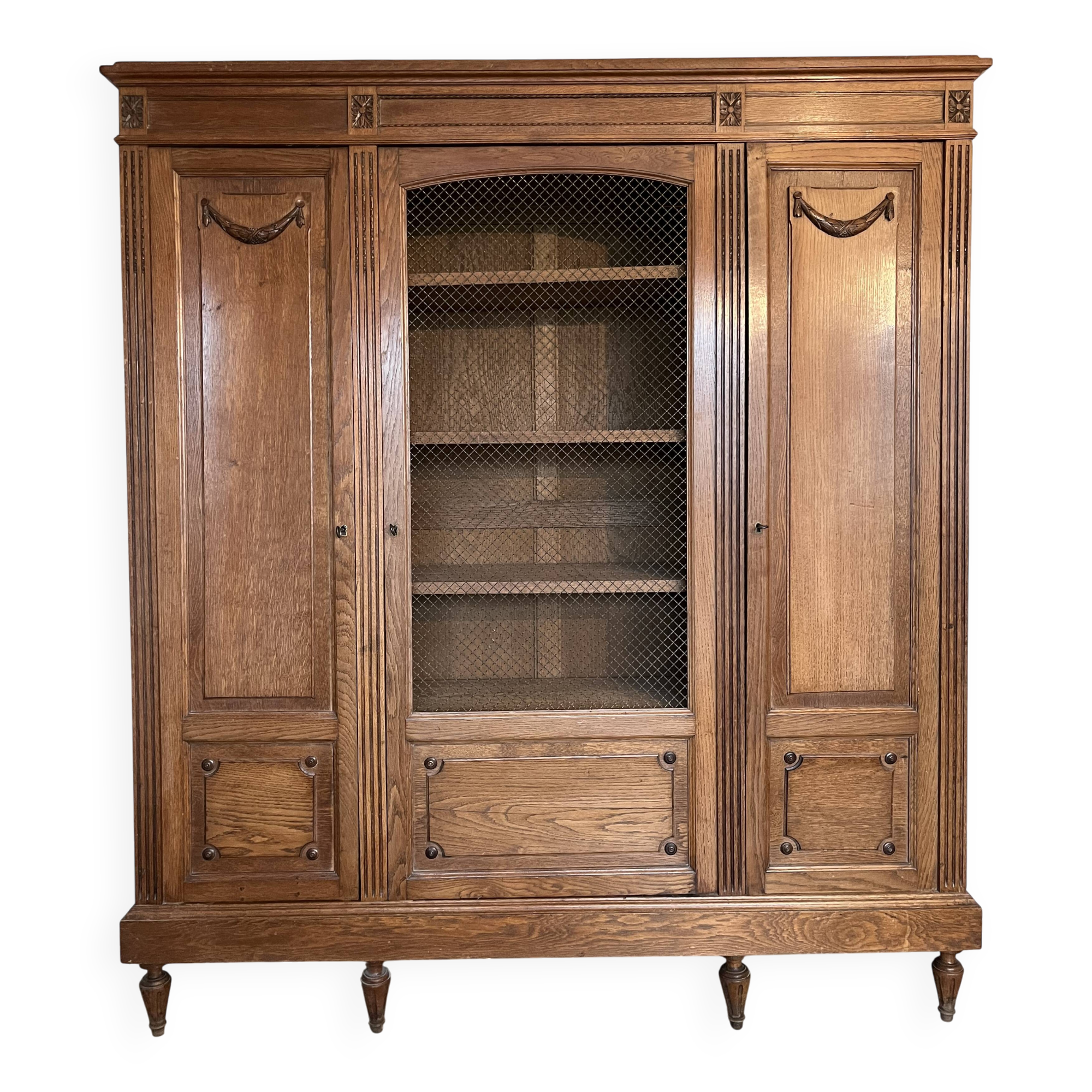 Three-door glass display cabinet with a grille in the Louis XVI style, antique and decorated.