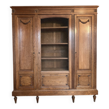 Three-door glass display cabinet with a grille in the Louis XVI style, antique and decorated.