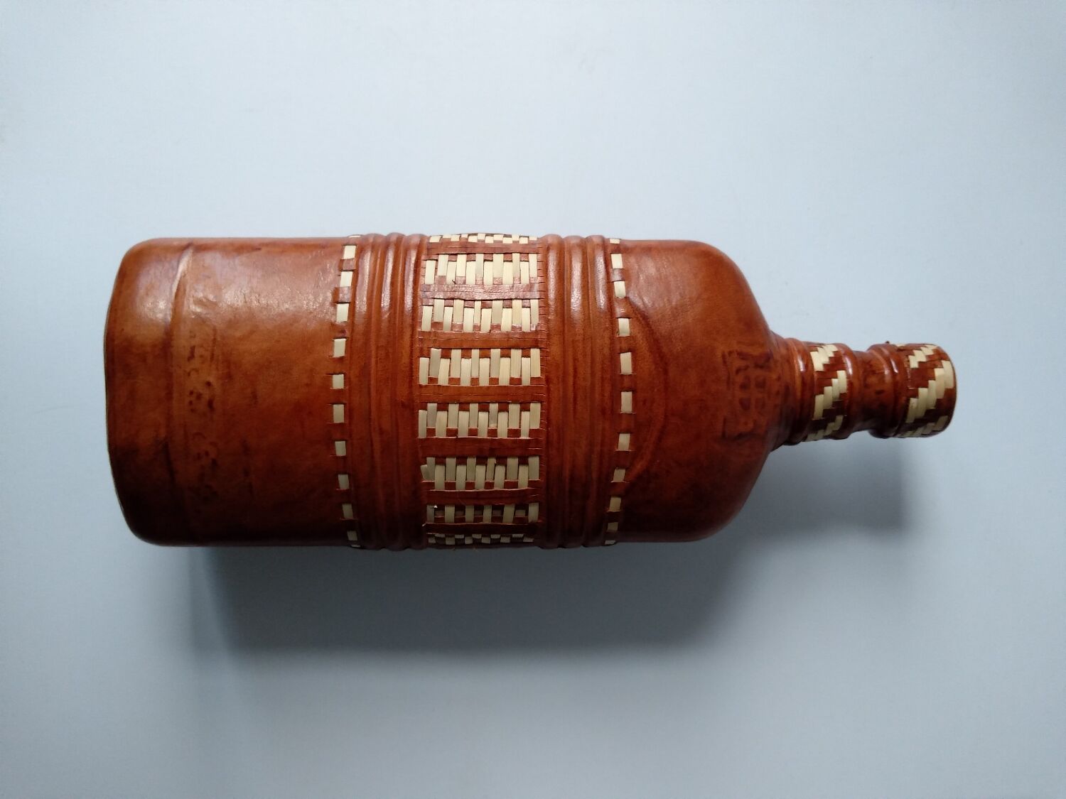 Vintage glass bottle covered with light brown leather and wicker