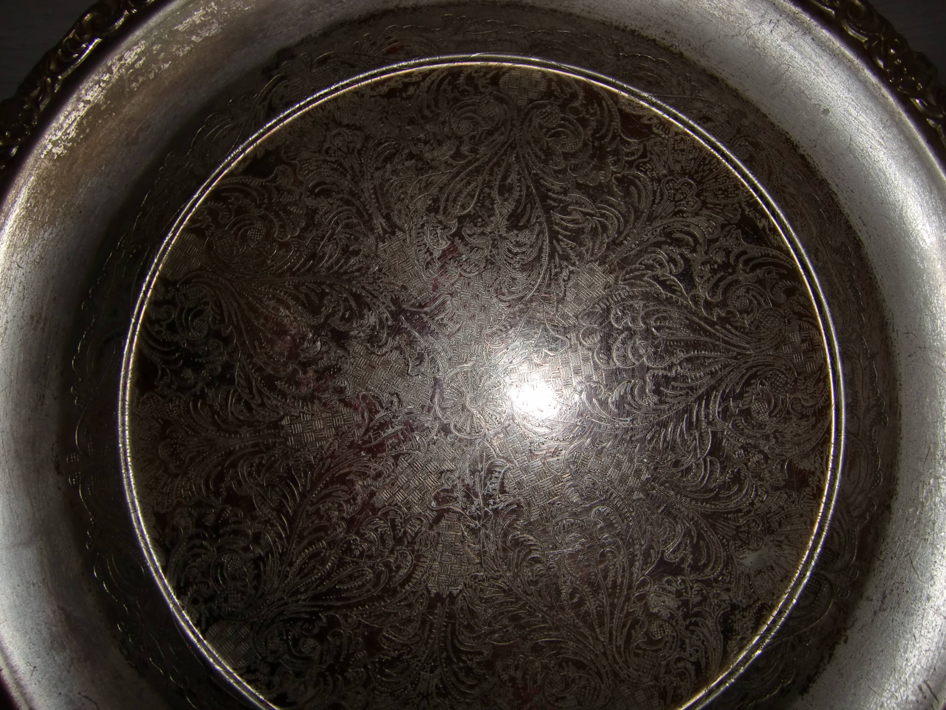 Large silver metal tray raised by a central foot