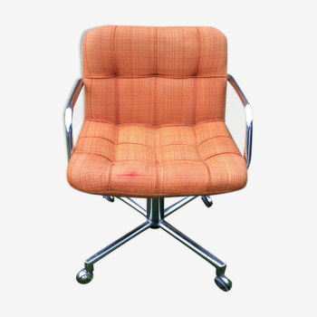 Fauteuil vintage à piétement en métal chromé pivotant et assises en tissu orange.