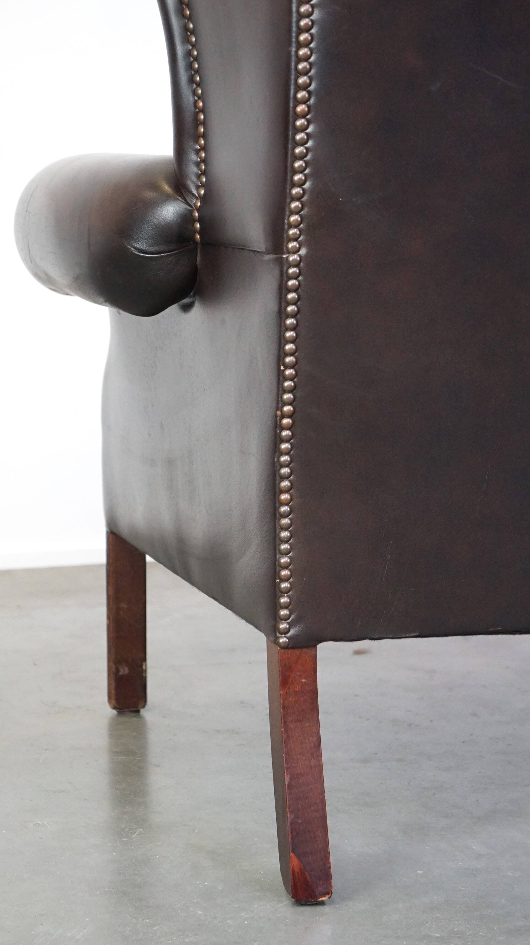 Chesterfield wing chair in dark brown leather with a luxurious appearance