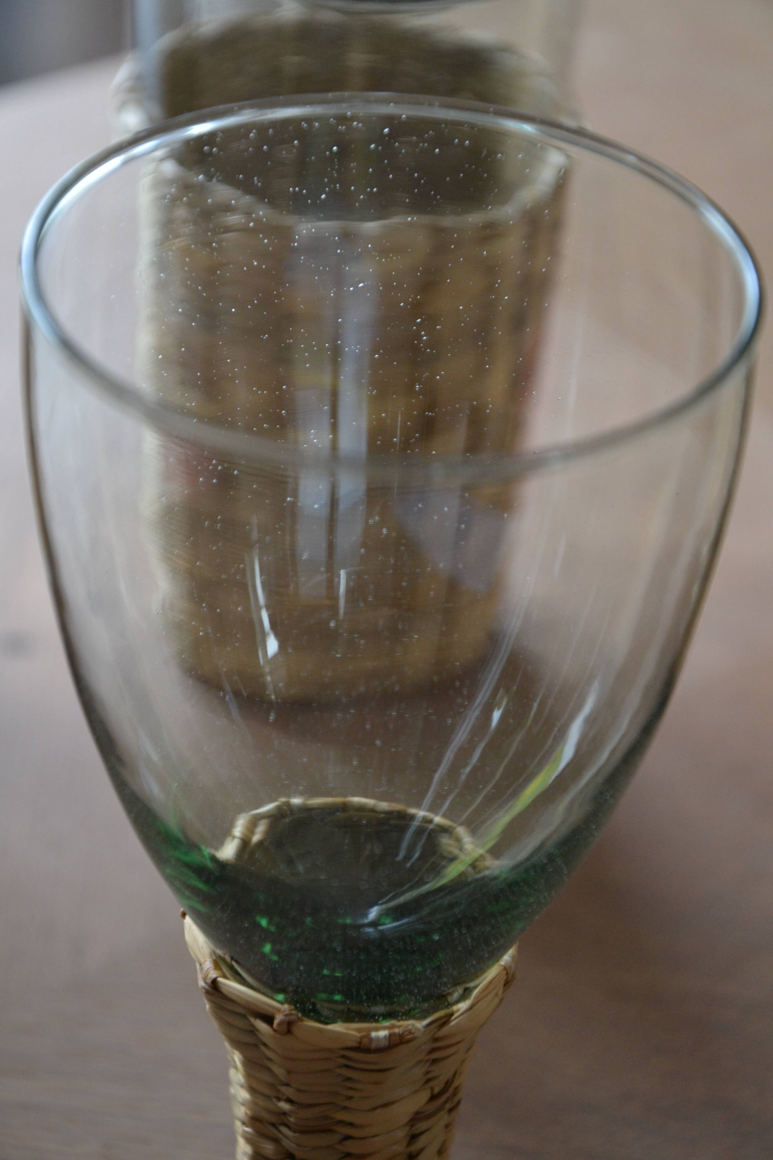 Four stemmed glasses surrounded by rattan.